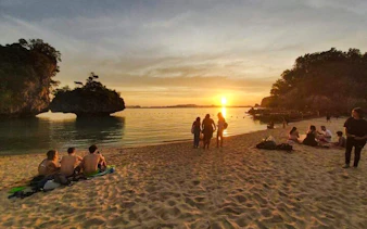 Sunset view at Hong Islands beach with people relaxing, Krabi longtail boat tour.