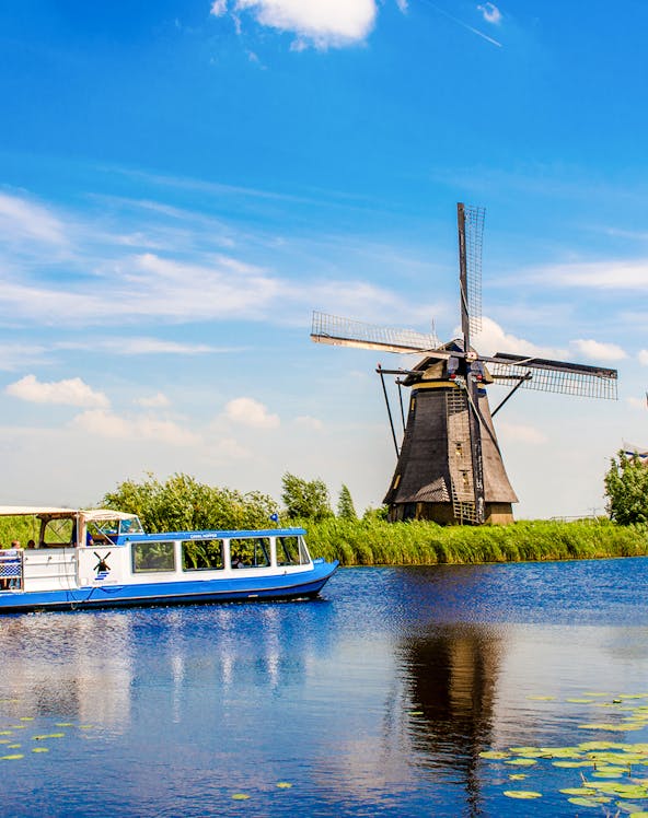 Canal tour boat passing a windmill at Kinderdijk, Holland, UNESCO World Heritage Site.