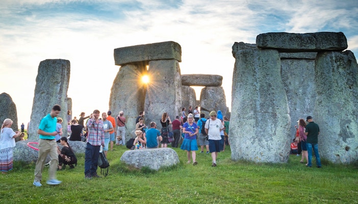 Tourists walking among Stonehenge stones during a day trip from London.
