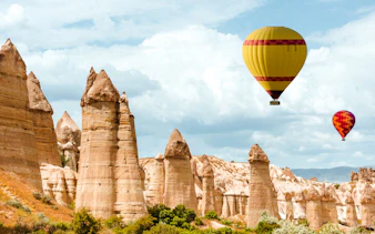 Hot air balloons over rock formations in Goreme, Cappadocia at sunrise.