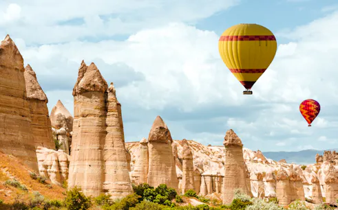 Hot air balloons over rock formations in Goreme, Cappadocia at sunrise.