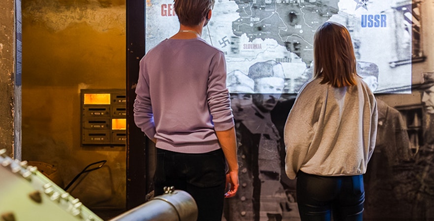 Visitors viewing a map of Poland's invasion at Oskar Schindler's Factory exhibit.