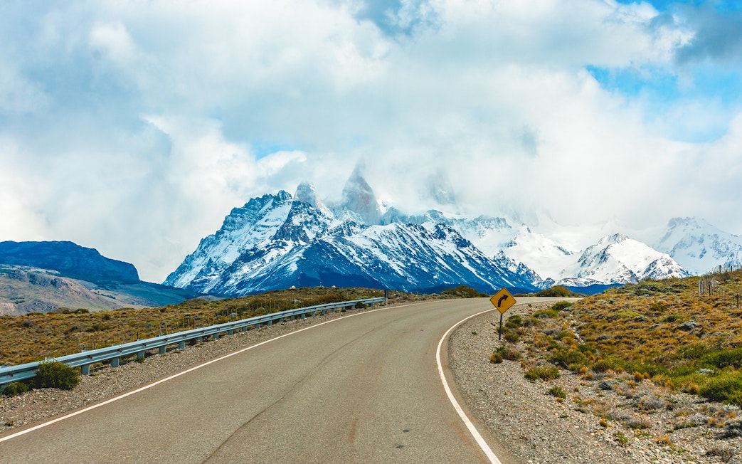 Road leading to Mount Fitz Roy in El Chaltén, Argentina, with snow-capped peaks in the background.