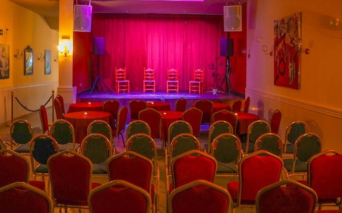 Flamenco Laietana stage with red chairs and tables in a dimly lit venue.