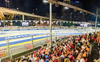 Crowd watching Formula 1 race at night, Singapore Grand Prix track view.