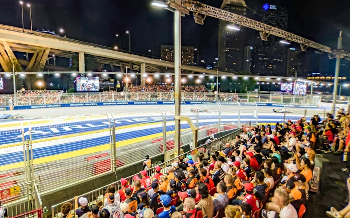 Crowd watching Formula 1 race at night, Singapore Grand Prix track view.