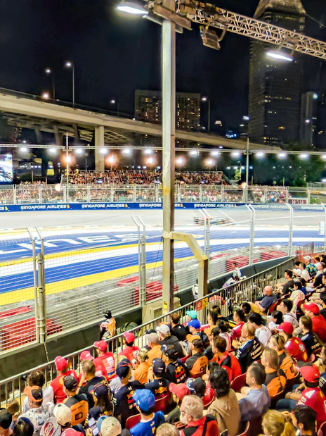 Crowd watching Formula 1 race at night, Singapore Grand Prix track view.