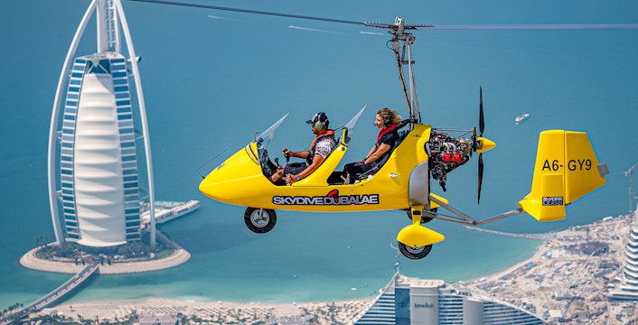 Gyrocopter flying over Dubai with Burj Al Arab in the background.