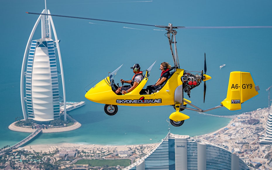 Gyrocopter flying over Dubai with Burj Al Arab in the background.