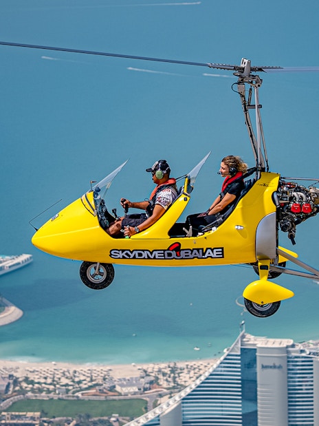 Gyrocopter flying over Dubai with Burj Al Arab in the background.