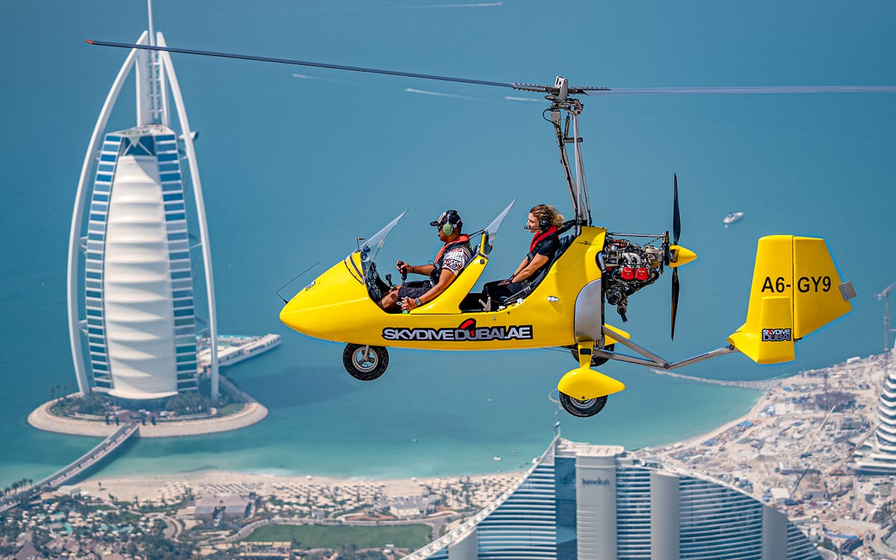 Gyrocopter flying over Dubai with Burj Al Arab in the background.
