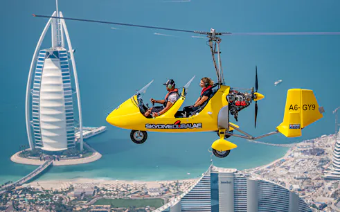 Gyrocopter flying over Dubai with Burj Al Arab in the background.