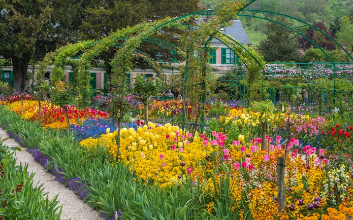 Giverny gardens with colorful flowers and Monet's house in the background, France.
