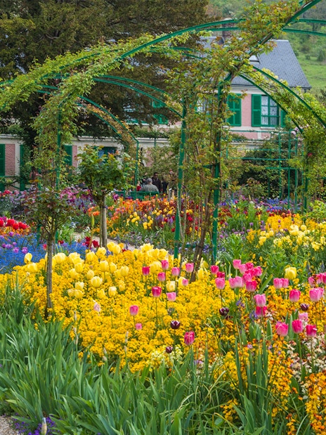 Giverny gardens with colorful flowers and Monet's house in the background, France.