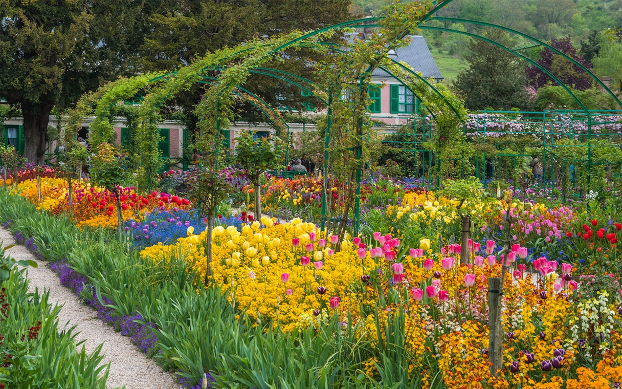 Giverny gardens with colorful flowers and Monet's house in the background, France.