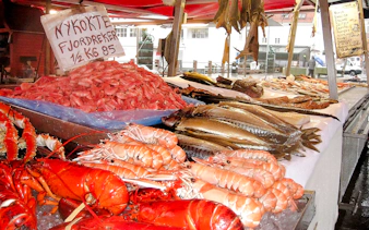 Seafood display at Bergen Fish Market with lobsters, prawns, and fish.