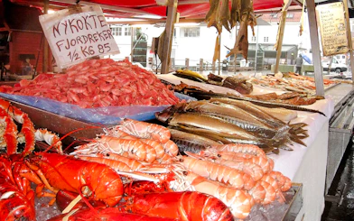 Seafood display at Bergen Fish Market with lobsters, prawns, and fish.