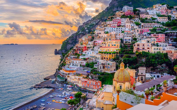 Colorful cliffside buildings in Positano overlooking the sea at sunset, part of the Sorrento, Positano, Amalfi, and Ravello tour from Naples.