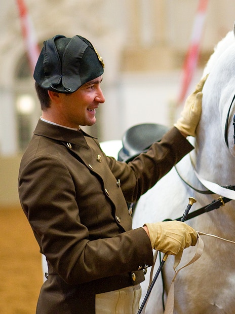 Two riders preparing a white horse at the Spanish Riding School.