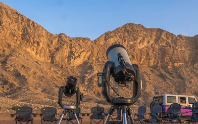Telescopes set up for stargazing in Mleiha desert with rocky landscape in the background.