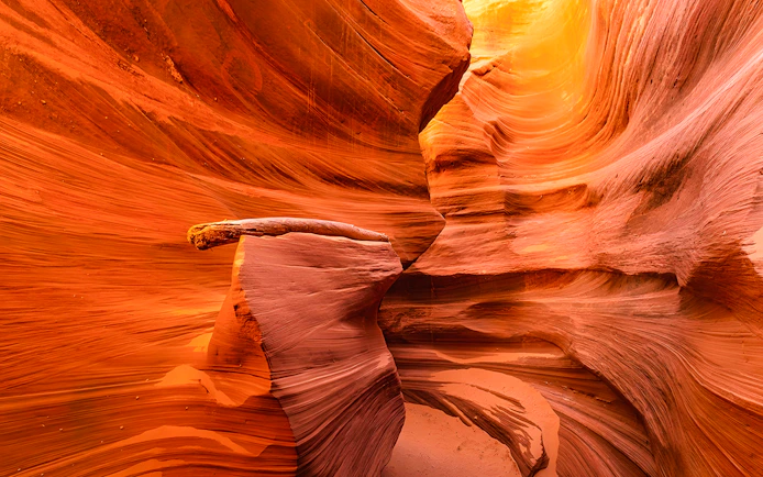 Waterhole Canyon's swirling red sandstone formations illuminated by sunlight.