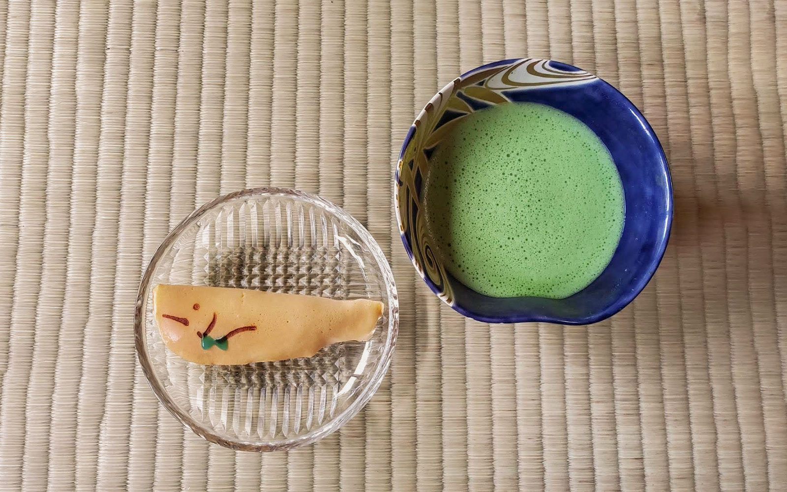 Matcha tea and traditional sweet on tatami mat during Kyoto tea ceremony.