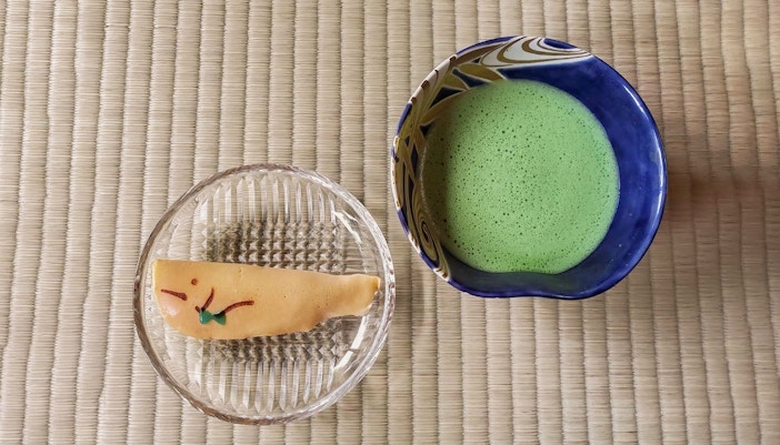 Matcha tea and traditional sweet on tatami mat during Kyoto tea ceremony.