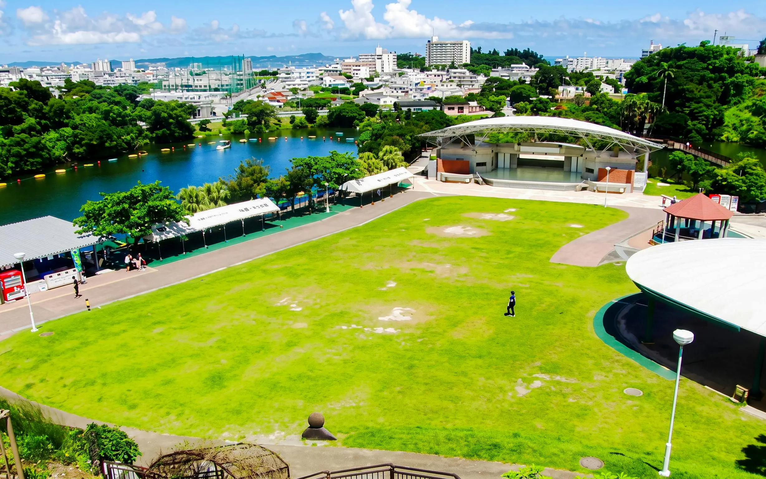 Okinawa Zoo & Museum outdoor stage and green lawn with cityscape in the background.
