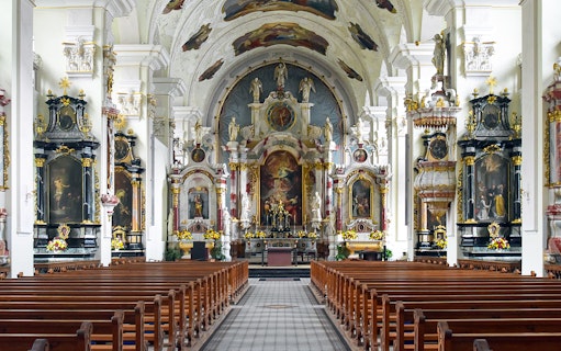 Interior of Engelberg Abbey church with ornate altar and pews, part of Zurich to Mt. Titlis tour.