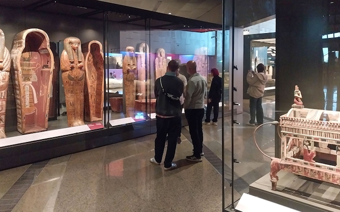 Visitors viewing ancient Egyptian sarcophagi at the Grand Egyptian Museum.