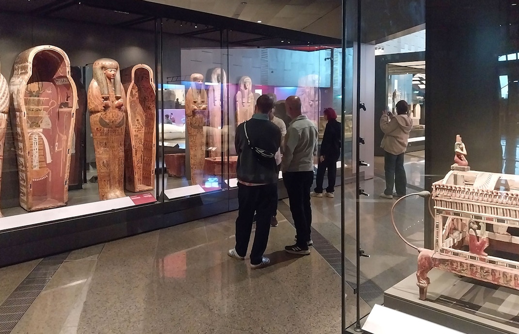 Visitors viewing ancient Egyptian sarcophagi at the Grand Egyptian Museum.