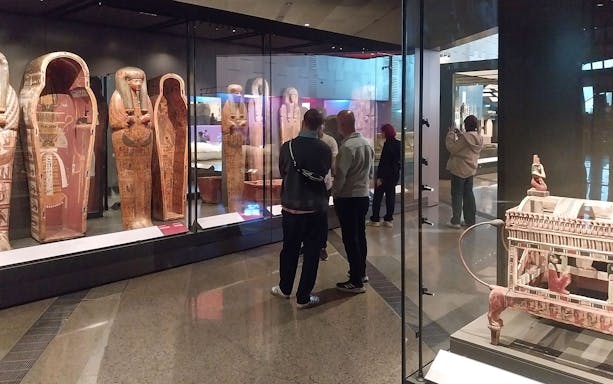 Visitors viewing ancient Egyptian sarcophagi at the Grand Egyptian Museum.