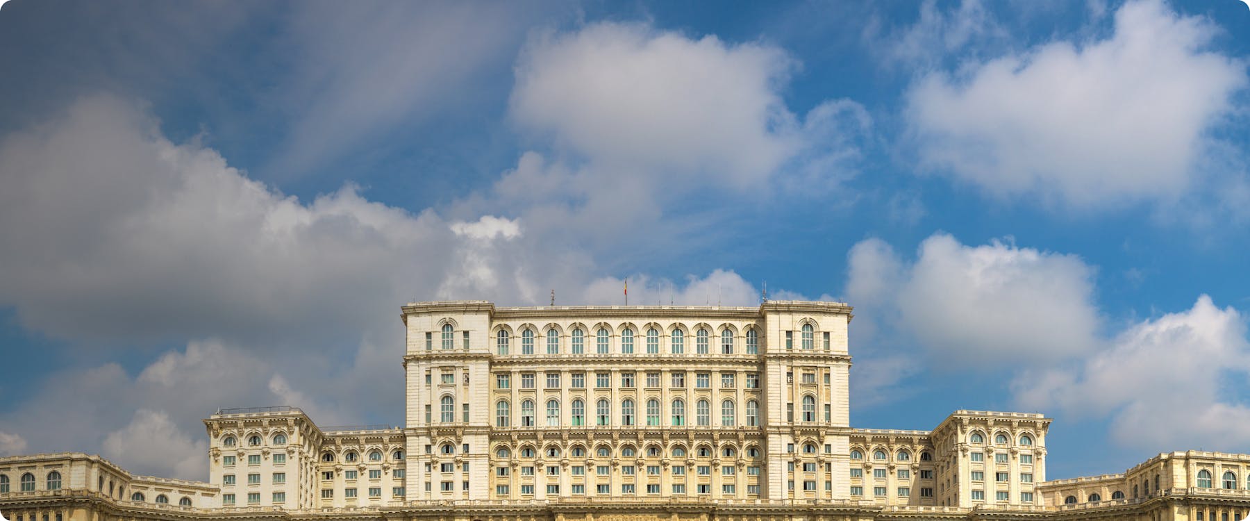 Palace of the Parliament in Bucharest under a blue sky.