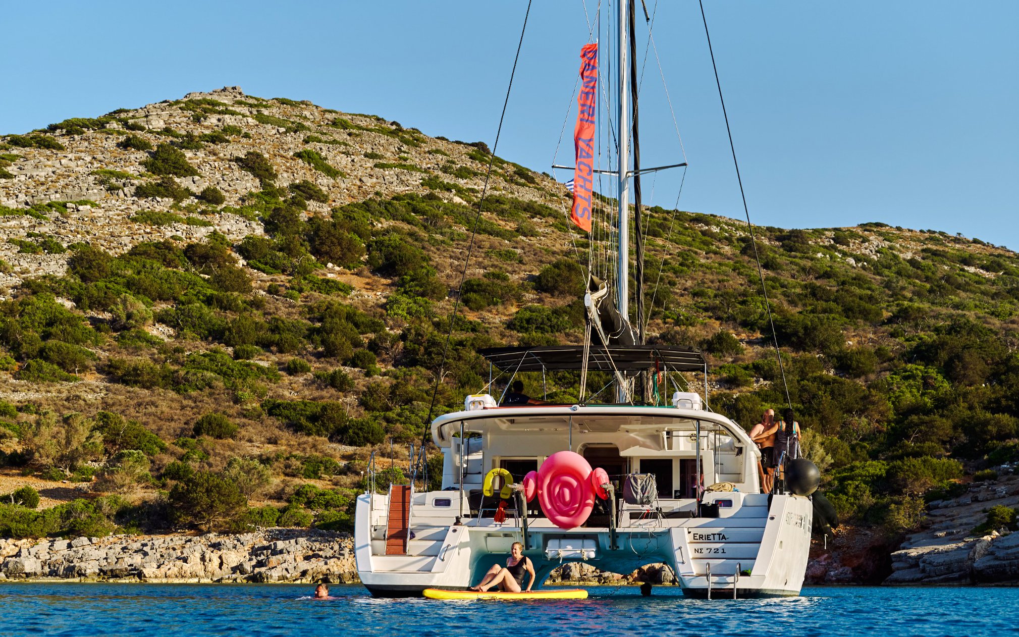 Catamaran anchored near Spinalonga, Crete with people swimming and relaxing.