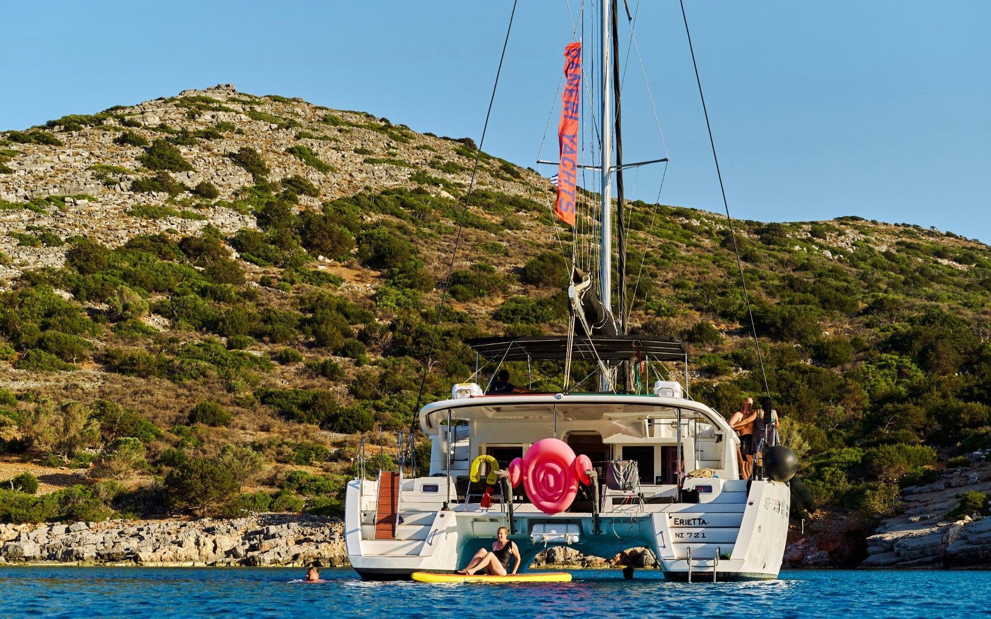 Catamaran anchored near Spinalonga, Crete with people swimming and relaxing.