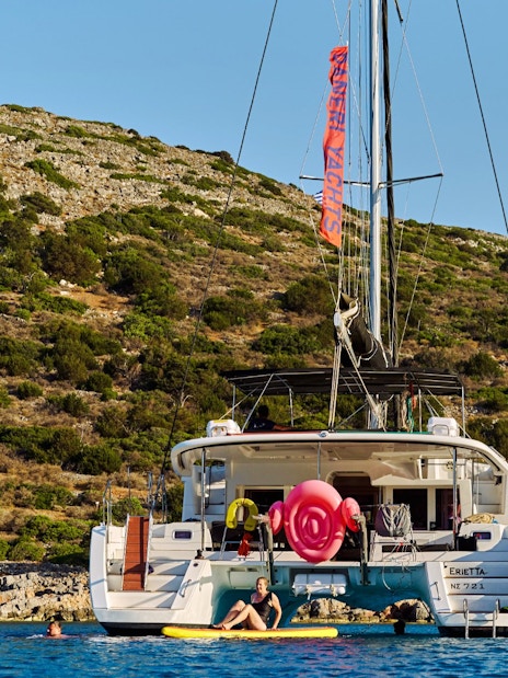 Catamaran anchored near Spinalonga, Crete with people swimming and relaxing.