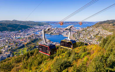 Ulriken cable cars ascending over Bergen, Norway with city and fjord views.