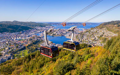Ulriken cable cars ascending over Bergen, Norway with city and fjord views.
