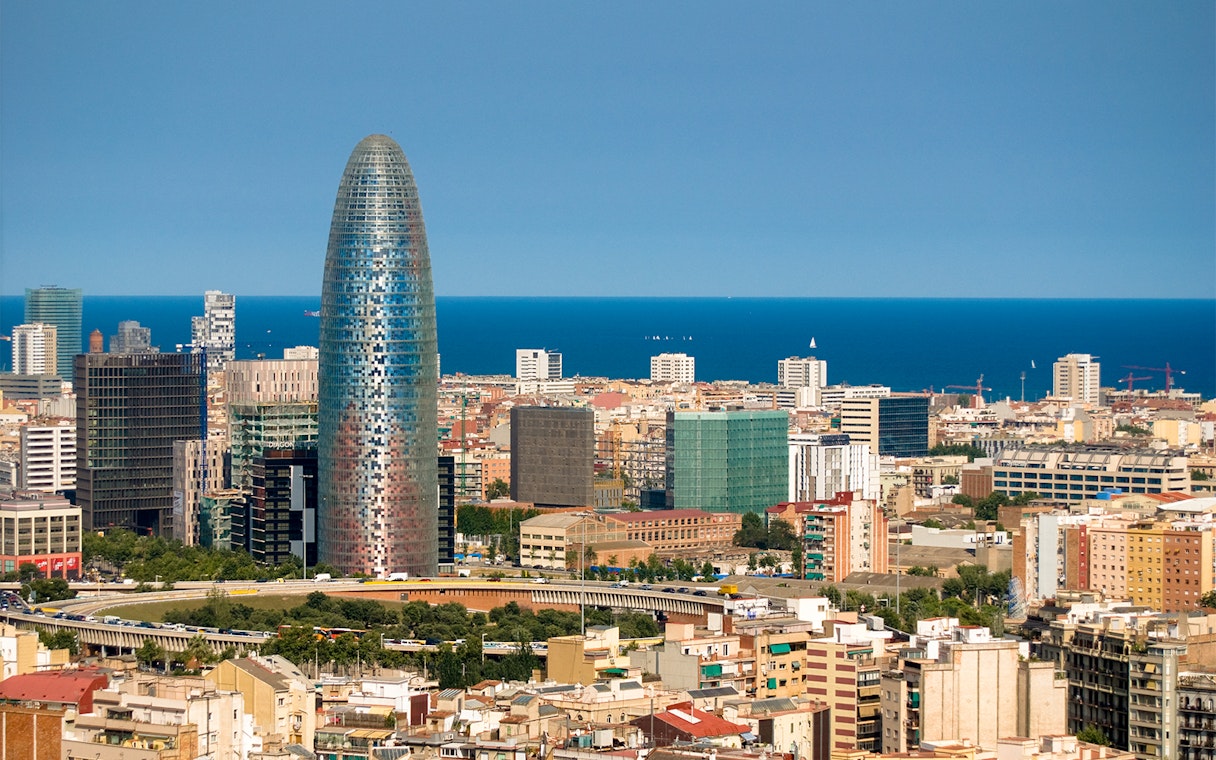 Torre Glories in Barcelona with cityscape and Mediterranean Sea in the background.