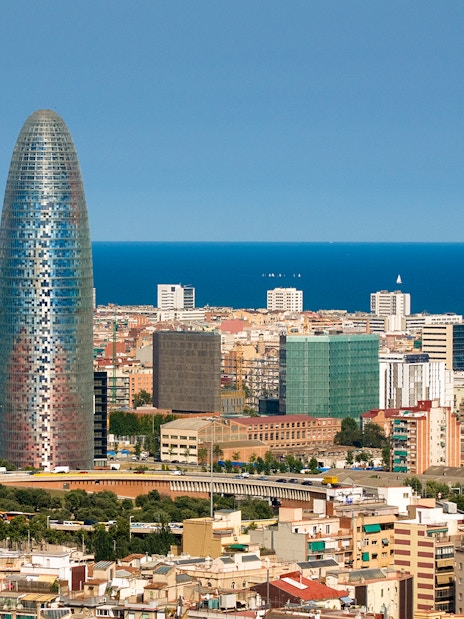 Torre Glories in Barcelona with cityscape and Mediterranean Sea in the background.