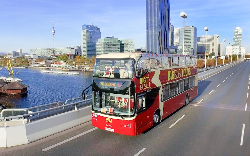 Big Bus tour in Vienna with city skyline and Danube River in the background.