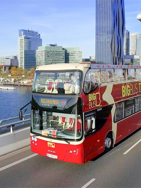 Big Bus tour in Vienna with city skyline and Danube River in the background.