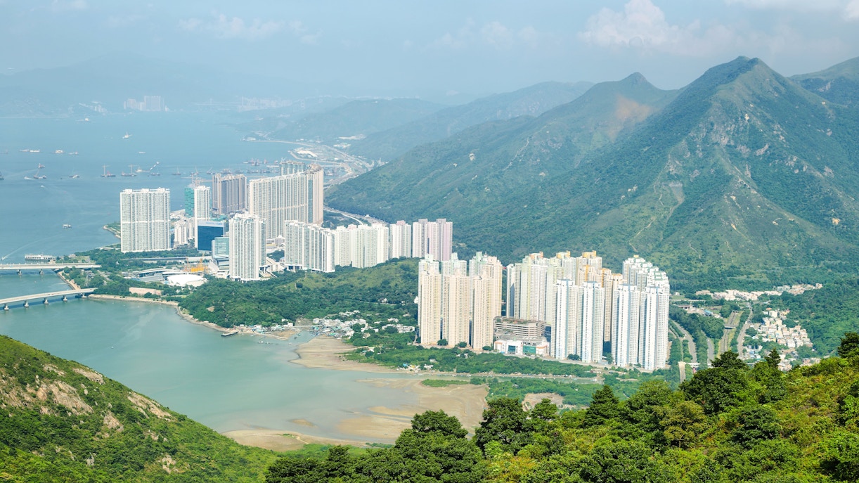 Aerial view of skyscrapers on Lantau Island with surrounding mountains and water.