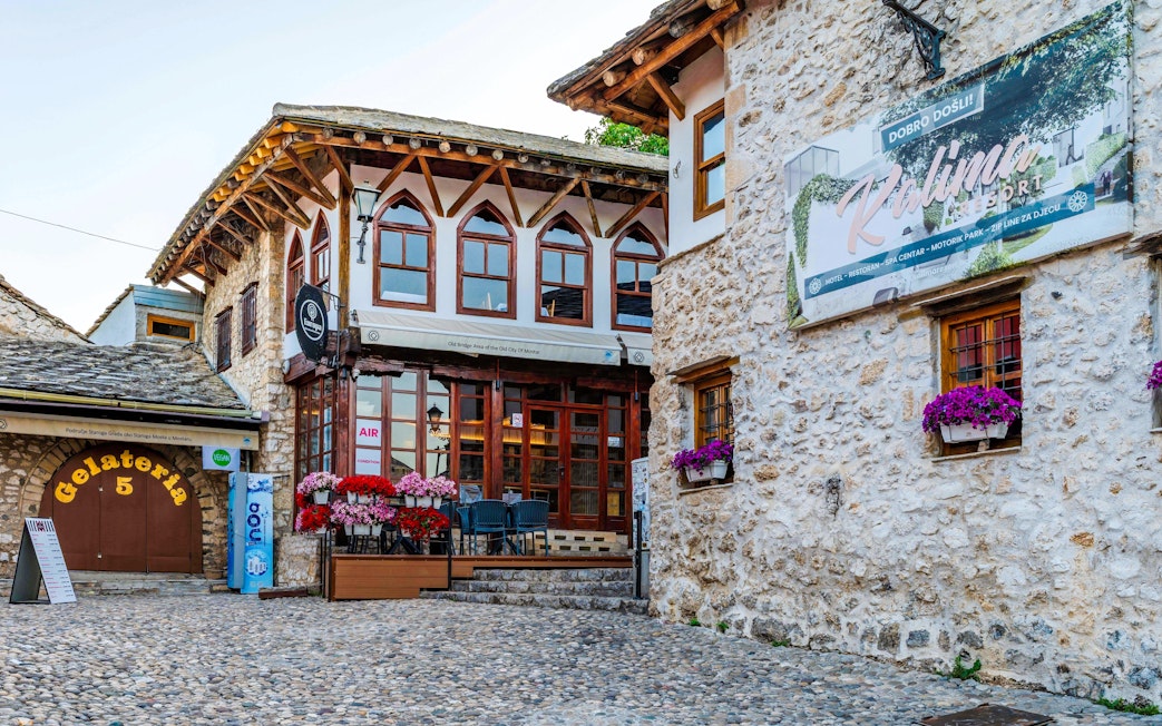 Street scene in the Old Town of Mostar with stone buildings and a gelateria.