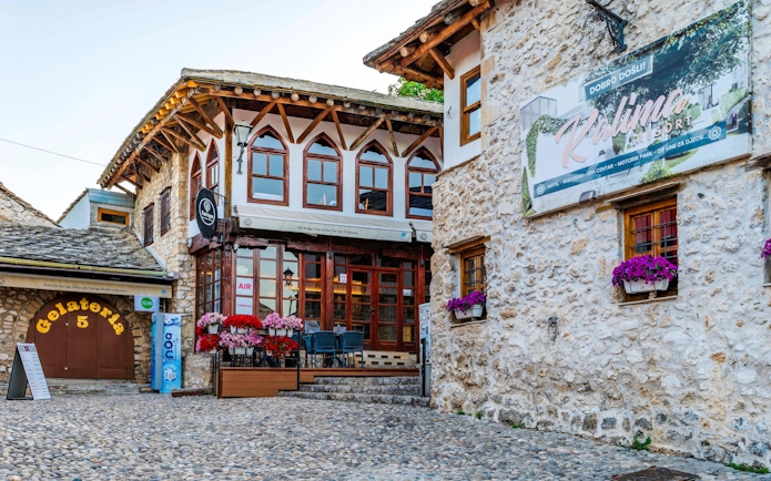 Street scene in the Old Town of Mostar with stone buildings and a gelateria.