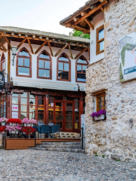 Street scene in the Old Town of Mostar with stone buildings and a gelateria.