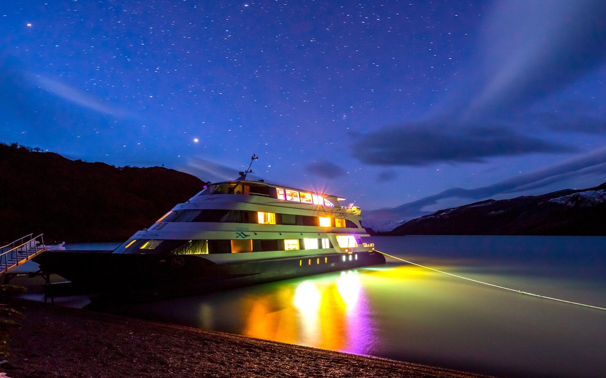 Boat illuminated at night during Spirit of the Glaciers tour, under a starry sky.