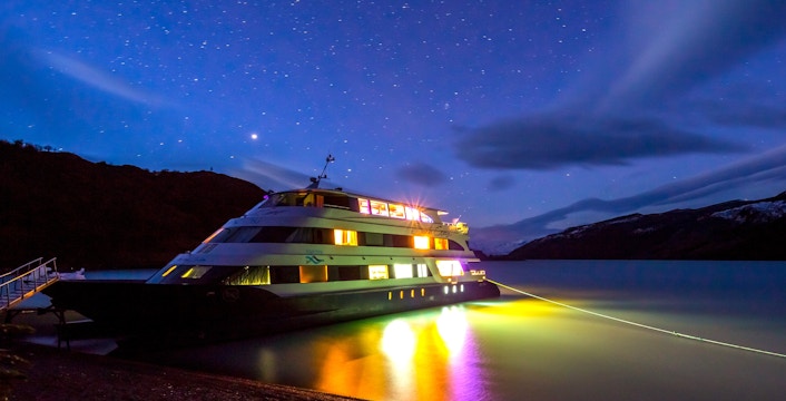 Boat illuminated at night during Spirit of the Glaciers tour, under a starry sky.