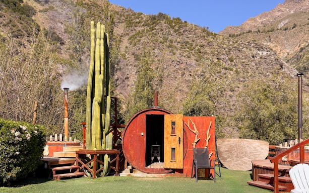 Glamping cabin with cactus and mountain backdrop in Cajón del Maipo, Chile.