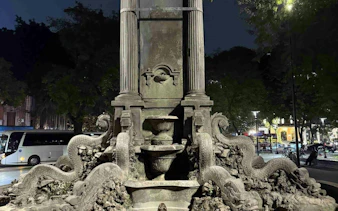 Stone fountain with dragon sculptures in Hanoi Old Quarter at night.
